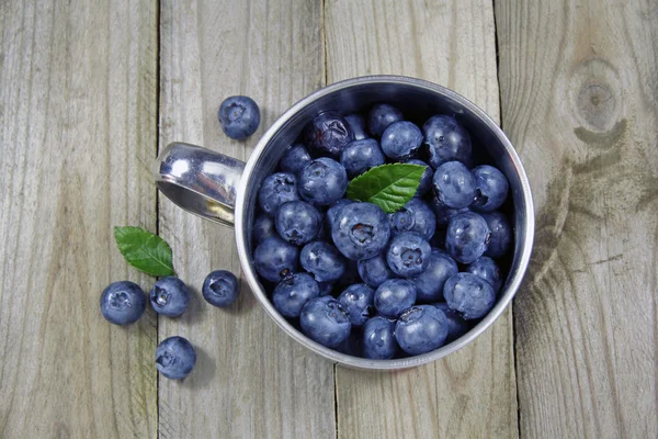 Blueberries in metal cup on wooden background — Stock Photo, Image