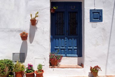 Mavi ahşap kapı ve çiçeklerle tipik İspanyol evin ön yüzü