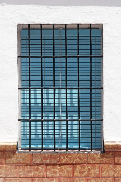 Vintage window with blue shutter behind bars — Stock Photo, Image