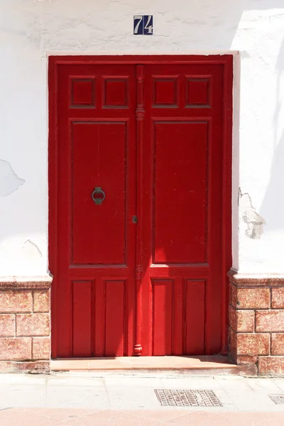 Rode houten deur in witgekalkte muur met Spaanse azulejos — Stockfoto