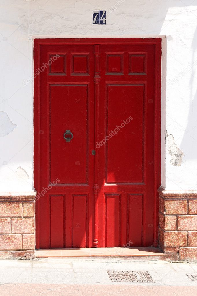 Red wooden door in whitewashed wall with spanish azulejos