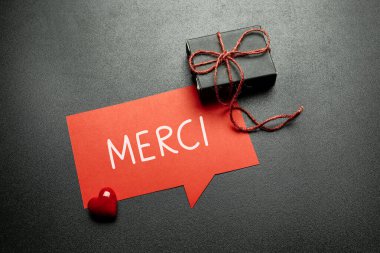 Merci (Fransızca olarak teşekkür ederim) siyah arkaplanda konuşma baloncuğu üzerine yazıldı