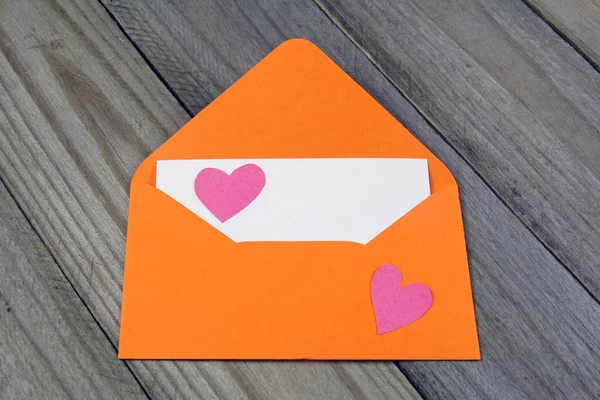 Love letter-orange kuvert med papper hjärta på tomt kort på trä bakgrund — Stockfoto