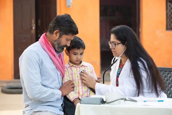 Steteskoplu Hintli kadın doktor, küçük çocuğun kalp atışlarını ya da nefeslerini kontrol ediyor babası ile birlikte Hindistan 'ın kırsal kesimlerinde sağlık hizmetleri konsepti tarafından muayene ediliyor.