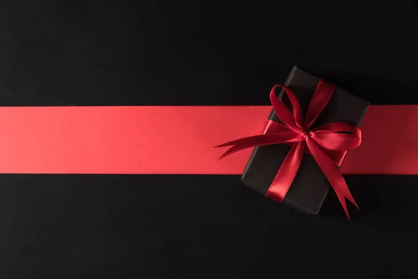 黑色星期五购物节及节礼的概念 礼品盒包装黑纸和红色蝴蝶结带礼物 工作室拍摄孤立在红色和黑色背景下 — 图库照片