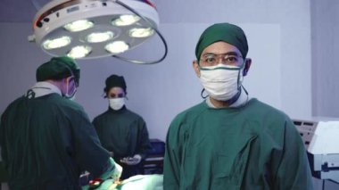 Kolları çapraz cerrah pozu veren doktor, hastanedeki kardiyovasküler acil cerrahi merkezi için elektrokoterapi ekipmanıyla ameliyathanede ameliyat yapan cerrahi doktor ekibi.