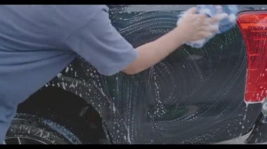 Araba yıkama servisini kapat araba yıkama servisini temizle araba yıkamada bezle araba yıka, genç işçi sabun temizle ve yıka.