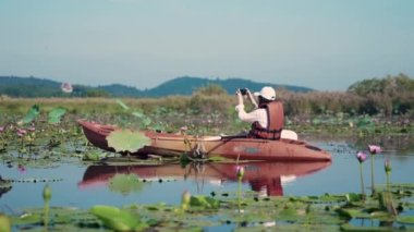 Gölde kano süren genç bir kadın yaz günü akıllı telefonuyla fotoğraf çekiyor. Macera seyahati keyfi konsepti, yaşam tarzı spor tatili.
