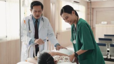 Hastane yatağında yatıp gülümseyen doktor ve hemşirelerle konuşan küçük, tatlı hasta bir kız. Hastane, sağlık ve salgın hastalıklar, dost canlısı doktor konsepti.