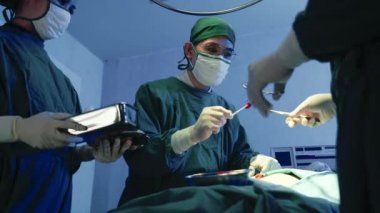 Tıbbi cerrahi doktor ekibi ameliyat yapıyor, grup cerrahı hastanede kardiyovasküler acil ameliyat merkezi için elektrokoterapi ekipmanıyla ameliyathanede çalışıyor.