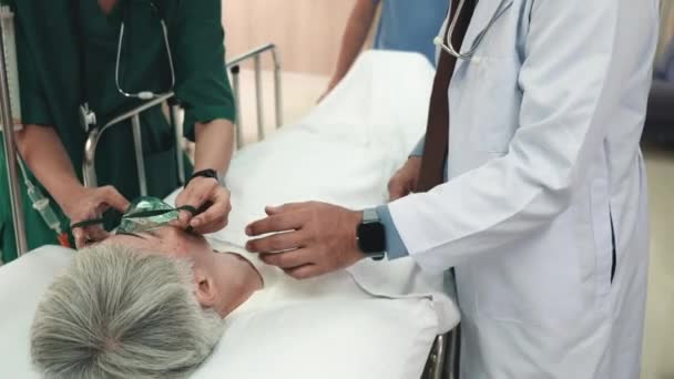 戴防护设备的医生戴上氧气面罩 将躺在床上的老年妇女 戴防护面具的麻醉师 戴防护面罩的病人连接起来 — 图库视频影像