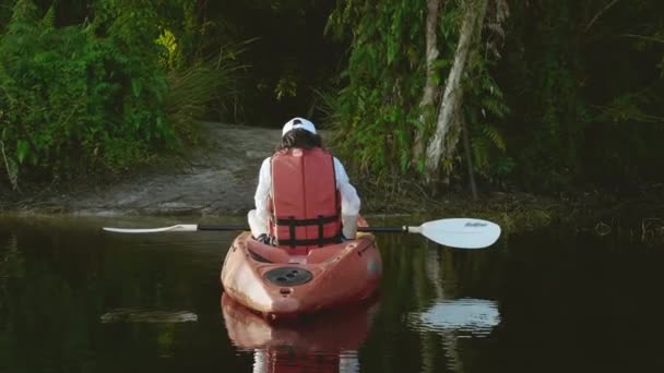 若い大人の女性が農村風景の夏の日に湖でカヤックカヌーを漕ぐ 冒険旅行レジャーコンセプトを楽しむ ライフスタイルスポーツ休暇 — ストック動画
