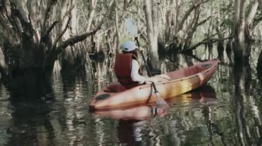 Yazın bir gölde kano süren genç bir kadın. Kırsal alanda, macera seyahati, eğlence konsepti, yaşam tarzı spor tatili.