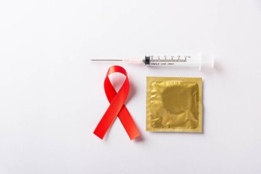 Kırmızı kurdele, HIV, AIDS kanseri farkındalığı, gölgeli kondom ve şırınga, beyaz arka planda izole edilmiş stüdyo çekimi, sağlık sigortası cinsel konsepti, Dünya AIDS Günü