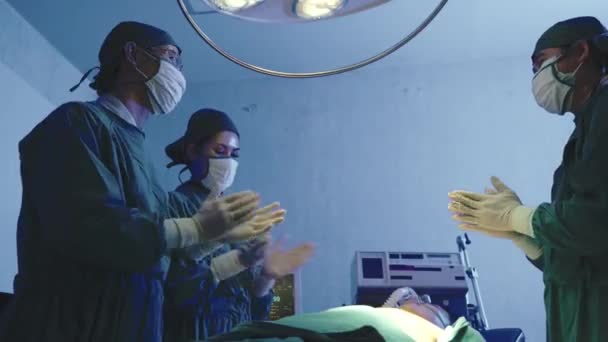 病院の手術室が成功した後 患者の拍手を立って滅菌手袋や保護顔マスクの外科医のグループは 医療チームの医師拍手手を祝福 — ストック動画