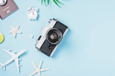 Düz açılı eski kamera filmleri, uçak, pasaport, denizyıldızı, deniz kabuğu gezginleri fotokopi alanı, yaz seyahati ve iş seyahati kavramına sahip mavi arka planda tropikal aksesuarlar.