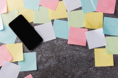 Beton arka planda modern siyah akıllı cep telefonu boş ekran ile birçok boş kağıt yapıştırma not listesi üzerinde, işletme akıllı telefon hatırlatma kavramı