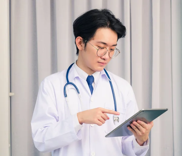 幸せなアジアの若い医師の肖像画の閉鎖ハンサムな男は 均一で聴診器首ストラップを保持し スマートデジタルタブレットをポイントし タブレットを見て 医療医学の概念 — ストック写真