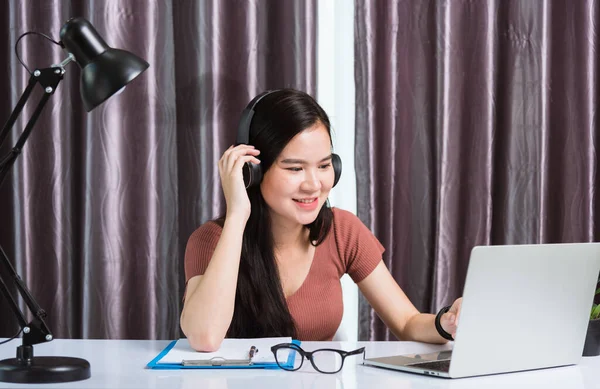 기사보기 집에서 일하는 아시아젊은 사업가가 헤드폰으로 통화를 하거나 사무실에서 책상에 — 스톡 사진