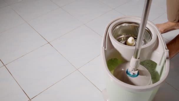 女人拿着拖把 用微型纤维头在桶里搅拌水 旁边是地板清洁液 然后在客厅扫地 — 图库视频影像