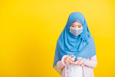 Asyalı Müslüman Arap, mutlu genç kadın portresi İslam dini peçe takıyor ve yüz maskesi takıyor hastalık koronavirüsü karantinaya alıyor izole edilmiş sarı ellere alkol spreyi sıkıyor