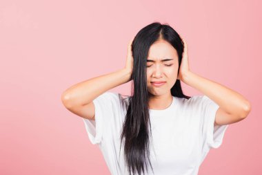 Asya portresi güzel hoş bir genç kadının kulakları kapalı, elleri kapalı, gözleri kapalı, stüdyo çekimi pembe arka planda, Taylandlı kadın kulaklarını fotokopi alanı ile kaplıyor.