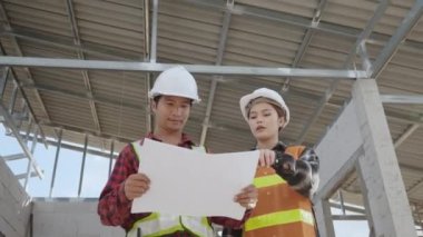 Mimar ve istemci, inşaat alanındaki binanın planıyla planı tartışıyor