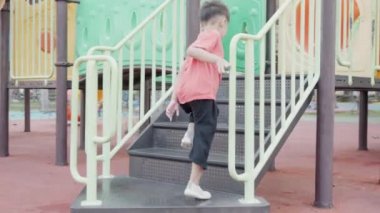 Asyalı çocuk kaygan bar oyuncağında oynarken gülümsüyor açık hava oyun parkında, mutlu anaokulu çocuğu yazın oyun parkında oynarken eğleniyor, küçük çocuk tırmanıyor.