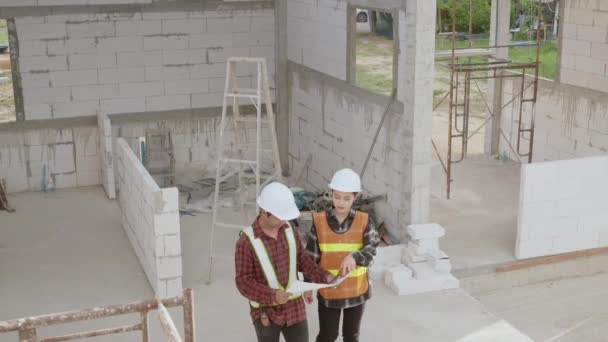 建設現場の建物の設計図と計画を議論する建築家とクライアント — ストック動画