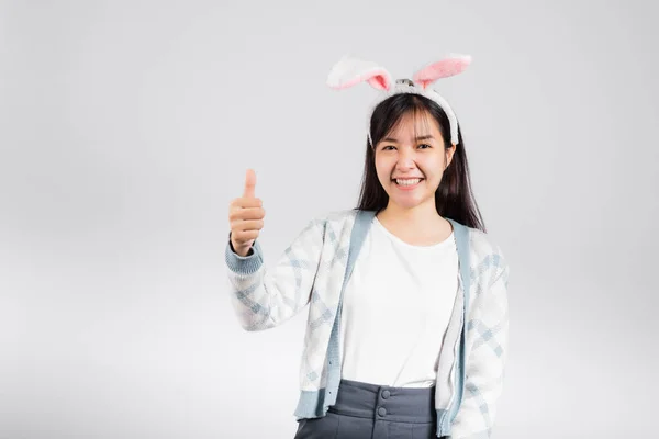 イースターの日の概念 笑顔幸せな女性身に着けているウサギの耳ショー親指アップのために良い兆候 スタジオショット隔離された上の白い背景とともにコピースペース — ストック写真