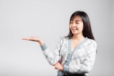 Gülümseyen mutlu kadın avucunun içinde bir şey tutuyor, portre Asyalı güzel genç bayan gösteri eli beyaz arka planda izole edilmiş jest stüdyosu çekimini gösteriyor.