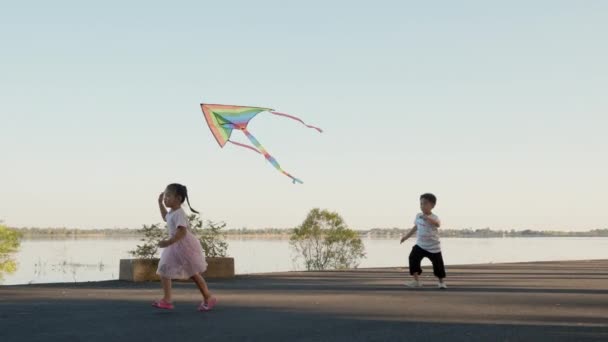 亚洲的两个兄弟 快乐的孩子 男孩和女孩 夏天的日落时分 他们带着风筝在户外奔跑 — 图库视频影像