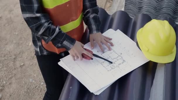 建築家とクライアントは 建設現場の床面に建物の青写真で計画を作成するのに役立ちます議論する アジアのエンジニアのフォアマンの労働者の女性は 紙のプロジェクト トップビューの描画について話す — ストック動画