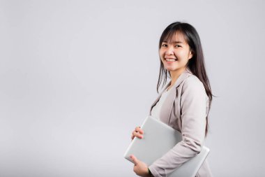 Kapalı dizüstü bilgisayarla gülümseyen, gülümseyen bir kadın, Asyalı mutlu bir genç kadının beyaz arka planda izole edilmiş gizli bilgisayar cihazı stüdyosunu kucaklaması heyecan vericiydi.