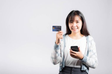 Gülümseyen bir kadın cep telefonu ve kredi kartı ile ödeme stüdyosu için kredi kartı, izole edilmiş beyaz arka plan, akıllı telefon alan ve online alışveriş yapan mutlu genç kadın.