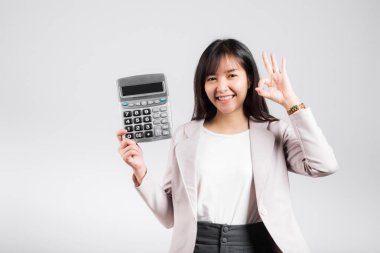 Vergi günü konsepti. Kadın, elinde elektronik hesap makinesi tutarak gülümsüyor ve heyecanlı bir jest yapıyor. Asyalı mutlu bir kadın stüdyo resmi. Beyaz arka planda izole edilmiş, hesap ve finans gelirleri var.