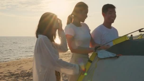 在夕阳西下的假日假期 快乐的朋友们一起在沙滩上搭起帐篷 一起出海度假 年轻的亚洲男子和女子在户外旅行 露营的人在户外生活 — 图库视频影像