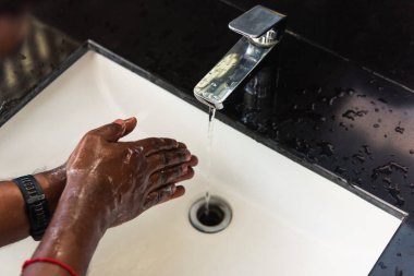 Siyah adamın ellerini yıkamak lavaboya sabun ve suyla ovmak salgın koronavirüsünün virüs yaymasını önlemek için, COVID-19 konseptini karantina temizliği için hijyen.