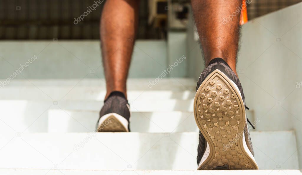 Close up athlete shoes of legs young sport runner black man step running up to climbing stairs doing training cardio sport workout at the outdoor street, healthy exercise before workout concept