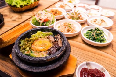 Bibimbap siyah ısıtılmış taş bir kase, Kore geleneksel bibibimbap - sebzeli pilav sığır eti, yumurta ve turşu, masaya konmuş sıcak Japon yemeği.