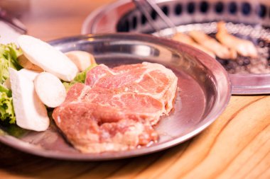 Tabakta çiğ domuz eti, Kore usulü sığır eti eti eti sobada barbekü, ahşap masa, Japon eti yahnisi veya Shabu restoranda barbekü yemeği.