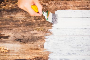 DIY, yakın plan kadın eli boya fırçası kullanıyor ya da eski ahşap rengi ahşap masa üzerine beyaz renge boyuyor