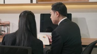 İki iş adamı birlikte sonuçları gösteren çizelge ve grafikleri tartışıyorlar. Asya iş dünyası iş ortaklığı konuşmaları ve masa başındaki başarılarının bütçe analizi grafiği.