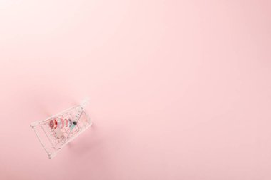 Aşı şişeleri ve koronavirüse karşı aşı için şırınga, ilaç hastalığı, Pembe arka planda izole edilmiş COVID-19 hastalığı aşısı olan alışveriş arabası.