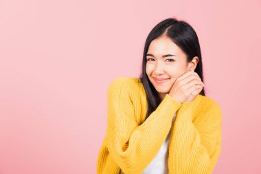 Mutlu Asyalı portre güzel sevimli genç neşeli melez kadın gülümse utangaç yüz ifadesi, stüdyo çekimi izole pembe arka plan, Taylandlı kadın utangaç zevk iki elini de yüze koy, kopyala boşluk