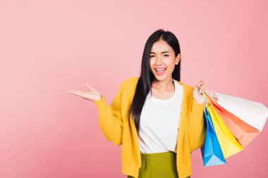Asyalı mutlu, güzel, alışveriş torbaları tutan, gülümseyen genç bir kadın portresi. Yazın elinde çok renkli bir şey var. Elle fotokopi çekilecek bir şey.