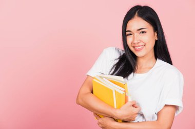 Güzel Asyalı genç bir kızın portresi gülümseyen kitaplar, çok renkli kitaplar tutan bir kadın, pembe arka planda izole edilmiş bir stüdyo resmi,