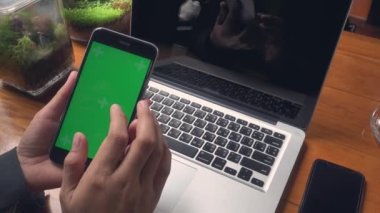 Dizüstü bilgisayarla çalışan iş kadını ve kafeteryadaki akıllı telefon yeşil ekranında bazı mesajları kontrol ediyor, iş kadını internet sitelerinde bilgi arıyor ve siyah ekranda kayıyor