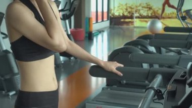 Asyalı güzel sporcu genç kadın kaslı sabah spor salonunda koşu bandında egzersiz yaparken kadın koşu bandında yürürken kardiyo üzerinde egzersiz yapıyor.