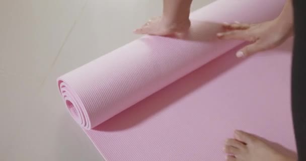 在客厅里做运动前或运动后翻滚粉色瑜伽垫的女人在客厅里做运动前或运动后做运动 在围产期通过运动瑜伽适合做运动女性的锻炼 运动健康的生活方式概念 — 图库视频影像